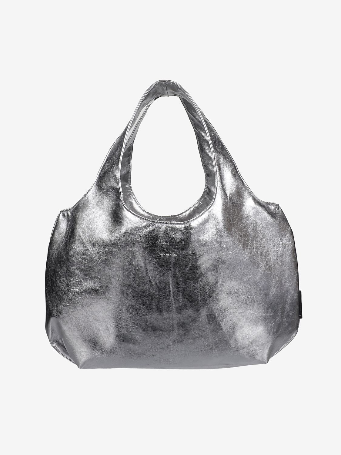 En statement bag som glir rett inn i hverdagsuniformen, uten å prøve for hardt. Bold Håndveske i sølv fra nederlandske Tinne+Mila har en glatt, skinnende overflate som gir antrekket et løft, enten du går for jeans, oversized blazer eller en enkel t-shirt-look. Den lette silhouetten og myke fasongen gjør den enkel å bruke, bære og style.  Inni vesken finner du en praktisk avtakbar clutch som holder styr på småting som telefon, nøkler eller lipgloss.